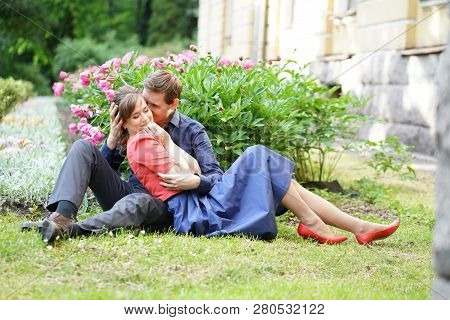 cute charming adult caucasian couple of lovers walking in the summer sunny park, kiss and hug with s
