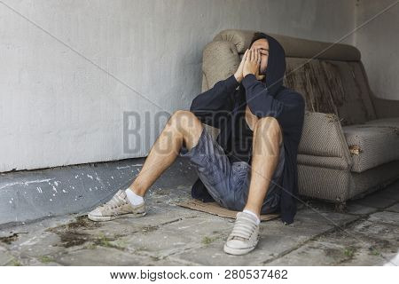Depressed, Desperate Young Man Sitting On The Building Rooftop Terrace, Wearing Hoodie, Holding Head