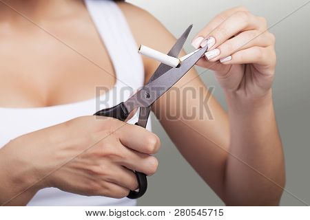 Stop Smoking The Concept. Young Beautiful Woman Cutting Cigarettes With Scissors Smiles, Isolated On