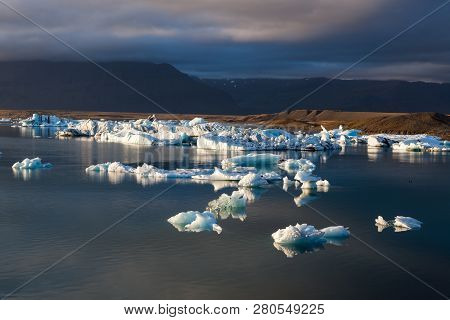 Cloudy Sunset Over Scattered Melting Icebergs Near Jokulsarlon Glacier Lagoon Shore. Global Warming