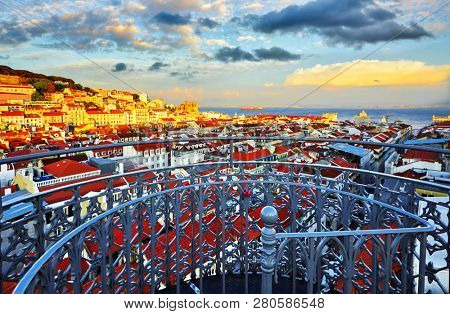Panorama of Lisbon, Portugal. View from Santa Justa Lift viewing platform at Alfama district old town and sea far away. Evening sunset with dramatic sky. Famous touristic destination landmark.