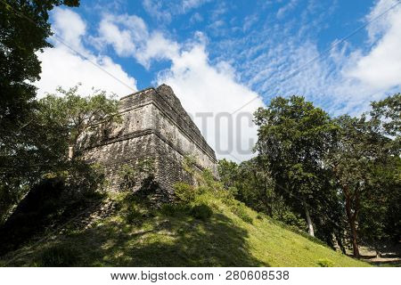 The Mayan Temple of Dzibanche in the forest of Mexico with blue sky behind.