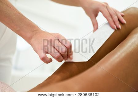 Woman Having Hair Removal Procedure On Leg Applying Wax Strip