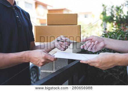 Delivery Mail Man Giving Parcel Box To Recipient, Young Man Signing Receipt Of Delivery Package From