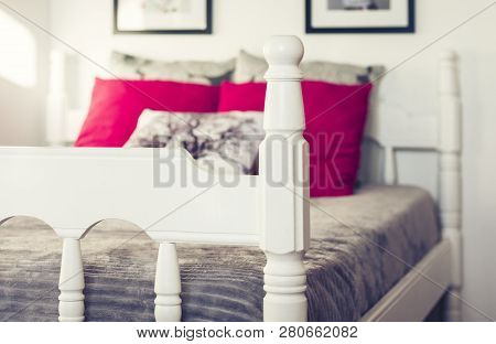 White Wooden Carved Bed With Gray Bedspread And Red Pillows