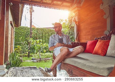 Man Using Smart Phone On A Terrace Sofa In Summertime.