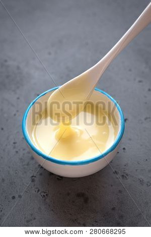 Condensed Milk Pouring In White Bowl. Sweet Vanilla Sauce, Condensed Or Evaporated Milk, Top View, C
