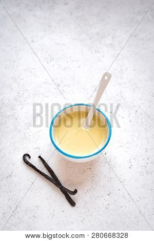 Vanilla Sauce Pouring In White Bowl. Sweet Condensed Or Evaporated Milk, Top View, Copy Space.