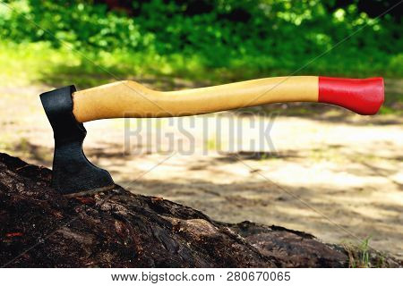 A Beautiful-shaped Ax Sticks Out In A Tree, With A Yellow Handle Close-up, On A Natural Background