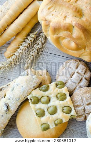 Assortment Of Traditional Italian Freshly Baked Crusty Loaves Of Bread And Buns With Ears On Wooden 