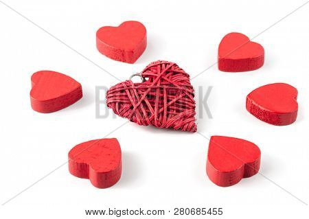 Group or red hearts isolated on white, six roughly carved wooden and one strawy