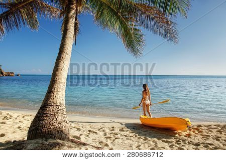 Young Woman In Bikini Standing On A Sandy Beach With Sea Kayak And Paddle, Nacula Island, Fiji