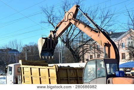 The Excavator Loads Crushed Stone In A Dump Truck Body. Iron Bucket Digging Machine
