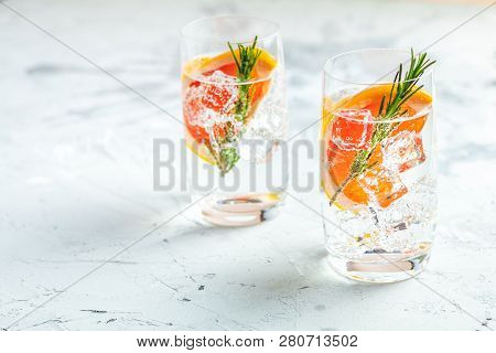Alcoholic Cocktail With Grapefruit, Soda, Ice, Gin And Rosemary, Light Gray Concrete Table Backgroun