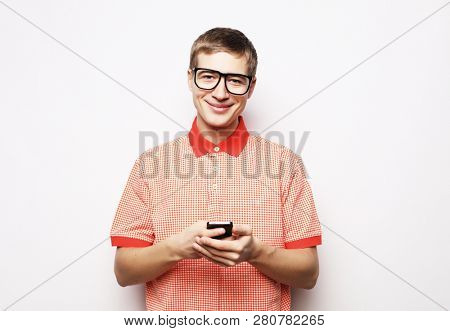  Happy young  man in glasses typing sms on white background