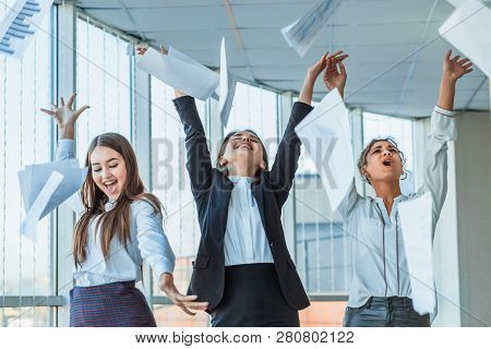 Three Young Beautiful Brunette Business Ladies In The Office. All Happy Dancing Dancing Up The Docum