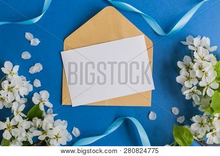 Mockup White Greeting Card And Envelope With White Spring Flowers And Blue Background
