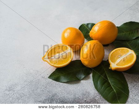 Orange Meyeri Lemons With Green Leaves In A Group On A Gray Background.