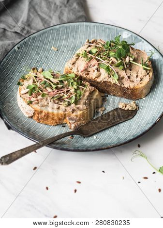 Two Toasts Duck With Prunes Rillettes Pate On White Bread With Sprouts And Various Seeds On A Blue P
