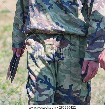 A Soldier In Camouflage Holding Throwing Knives