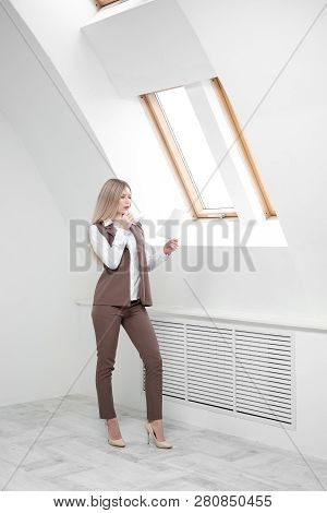 Blonde Girl In A Business Suit Works On A Computer In A White Bright Office.