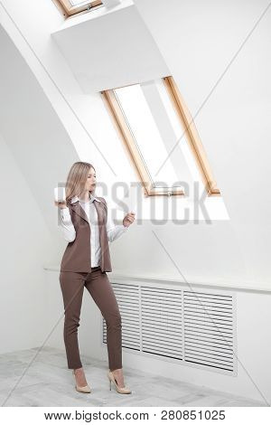 Blonde Girl In A Business Suit Works On A Computer In A White Bright Office.