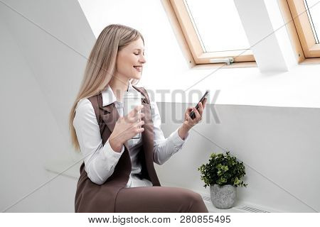 Blonde Girl In A Business Suit Works On A Computer In A White Bright Office.