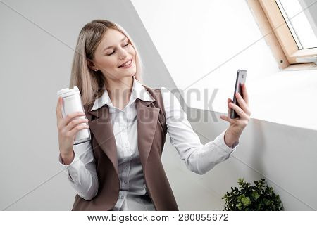 Blonde Girl In A Business Suit Works On A Computer In A White Bright Office.