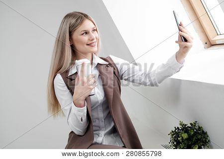 Blonde Girl In A Business Suit Works On A Computer In A White Bright Office.