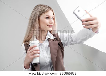 Blonde Girl In A Business Suit Works On A Computer In A White Bright Office.