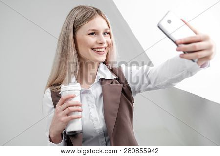 Blonde Girl In A Business Suit Works On A Computer In A White Bright Office.