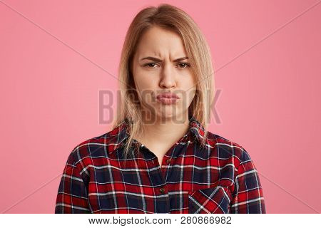 Indoor Shot Of Displeased Blonde Woman Pouts Lips And Frowns Face, Doesnt Like Something, Has Sullen
