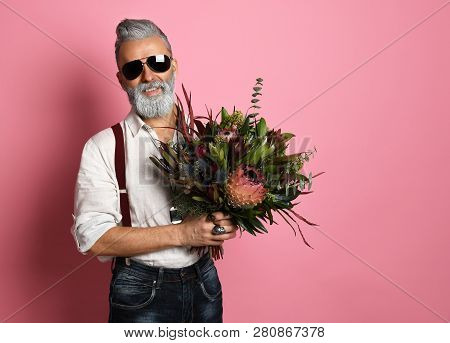Handsome Older Stylish Bearded Man In White Shirt Holding A Bouquet Of Flowers Over Pink Background 