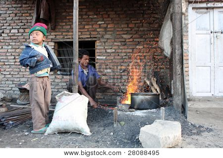 KATHMANDU, Nepál - 7. ledna: Pracovník Štěpán Kumar a jeho syn Pavel (vlevo) brusný nástroj chudý