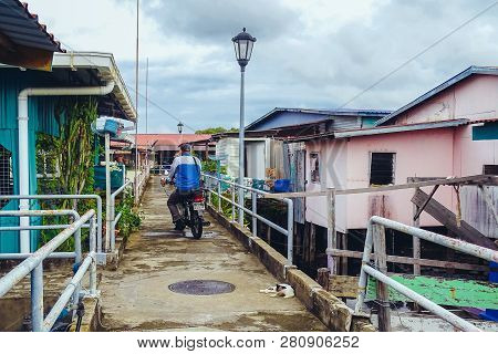 Labuan,malaysia-jan 15,2019:men Ride A Motorcycle In Wooden Houses Built On Stilts On Water In Patau