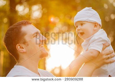 Baby with faher in the park in the rays of sunset. Toddler on the nature outdoors. Backlight. Summertime family  scene