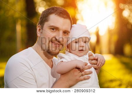 Baby with faher in the park in the rays of sunset. Toddler on the nature outdoors. Backlight. Summertime family  scene