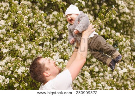 Baby with faher in the park in the rays of sunset. Toddler on the nature outdoors. Backlight. Summertime family  scene