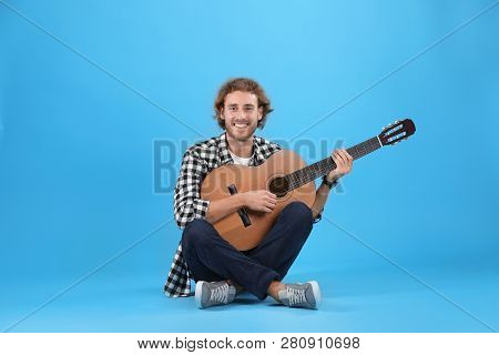 Young Man Playing Acoustic Guitar On Color Background