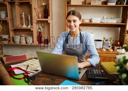 Portrait Of Female Small Business Owner Using Laptop And Looking At Camera In Shop, Copy Space