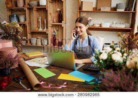 Portrait Of Female Small Business Owner Using Laptop And Speaking By Phone In Flower Shop, Copy Spac
