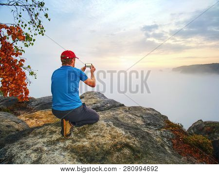 Hiker Takes Selfie Photo, Fall Nature Adventure. Man Sit On Stone On Mountain Sumit  Daybreak Horizo