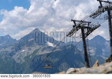 Cableway On Mountaintop In Cloudy Weather. Modern Ropeway With Benches In Amazing Mountainous Terrai