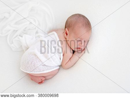 Cute newly arrived baby lying, wrapped in blanket