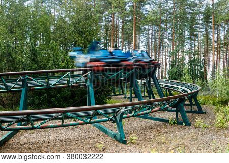Ride Roller Coaster In Motion In Amusement Park At Summer Day