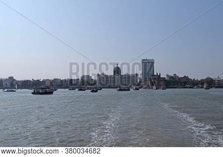 MUMBAI, INDIA - FEBRUARY 15, 2020: Taj Mahal hotel, Gateway of India and tourist boats in water of Arabian Sea  in Mumbai, India