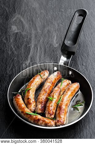 Delicious  Pork Chipolatas Sausages In A Frying Pan On Black Stone Background