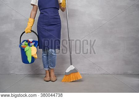 Professional Cleaning Service. Cropped Shot Of Woman In Uniform And Yellow Rubber Gloves Holding Bro