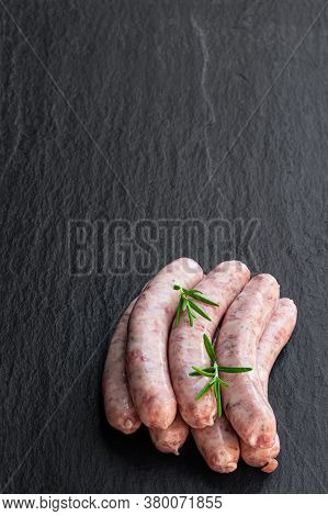 Pork  Sausages Chipolatas On Black Stone Background