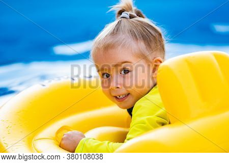 Child In Swiming Pool In Yellow Inflatable Waist Baby Swim Float On Summer Day. Children In Swimming